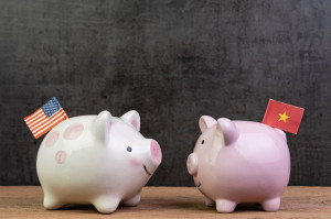 US and China trade war or tariffs negotiation concept, piggy bank with United state national flag face to face with one with China flag on wood table dark background with copy space
