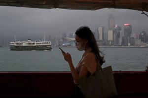 홍콩 빅토리아만 너머로 도심 건물들이 보이는 가운데 한 여성이 지나가고 있다.