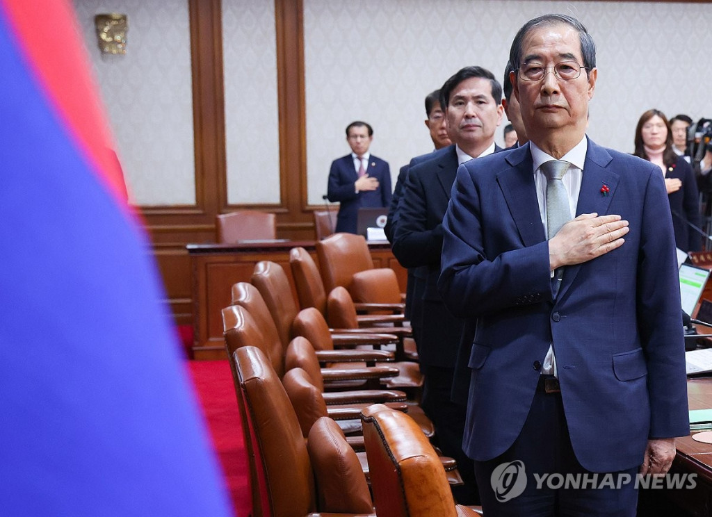 한덕수 대통령 권한대행 국무총리가 19일 정부서울청사에서 열린 임시 국무회의에서 국기에 경례하고 있다. [대통령통신사진기자단]