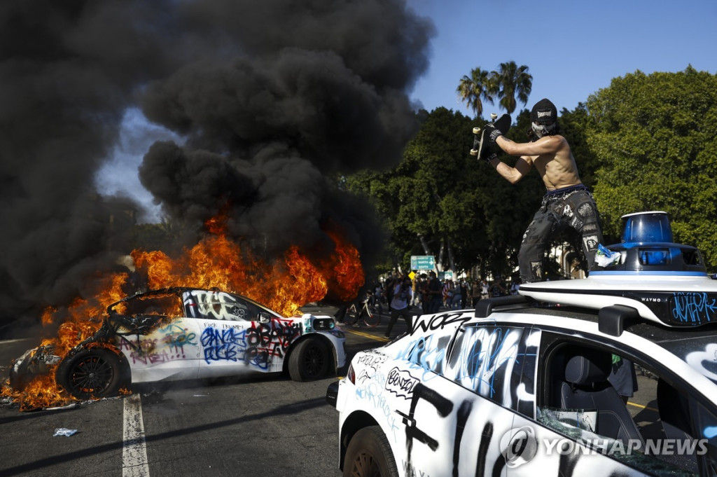 시위대원이 자율주행차 웨이모를 부수고 있다.[EPA=연합]