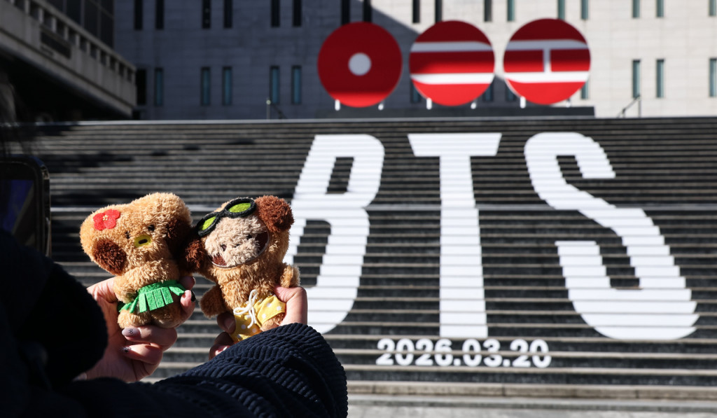 22일 서울 종로구 세종문화회관 계단에서 외국인 관광객들이 오는 3월 3년 9개월 만에 ‘완전체’로 돌아오는 그룹 방탄소년단(BTS)의 컴백을 알리는 홍보물을 기념촬영하고 있다. [연합]