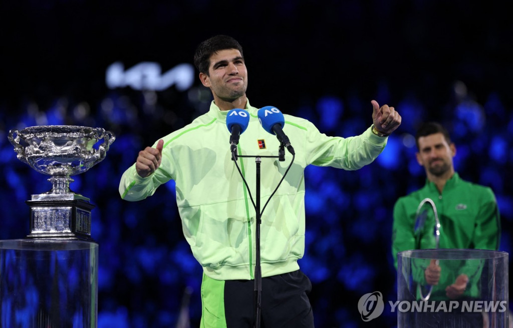 호주오픈 남자단식에서 우승한 카를로스 알카레스가 시상식에서 노바크 조코비치가 지켜보는 가운데 포즈를 취하고 있다.[로이터=연합]